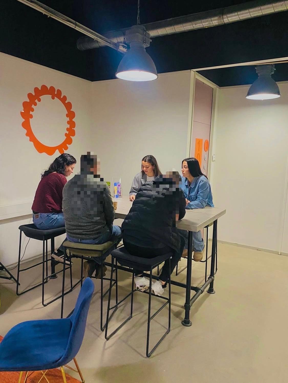 Begeleiders en cliënten aan tafel in gesprek
